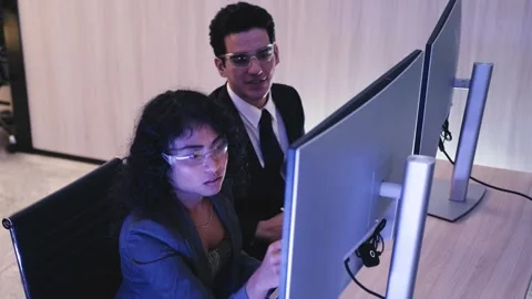 Two professionals in modern office collaborate coding at dual monitors Stock Footage 318578708