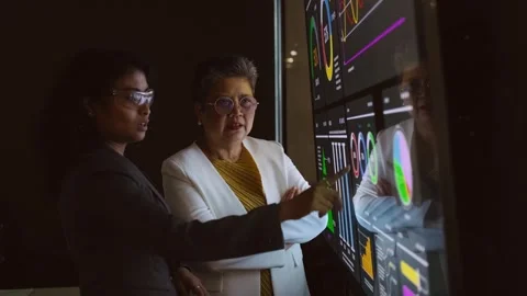 Two professionals review interactive data dashboards on a large touchscreen Видео 319066251