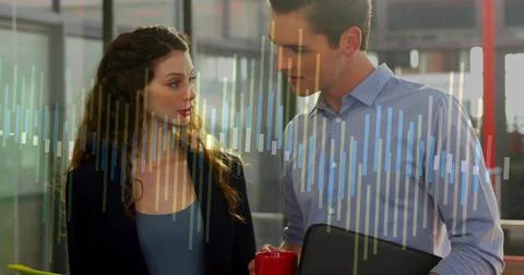 Two professionals reviewing data chart overlay in office, holding red coffee mug Stock Photos