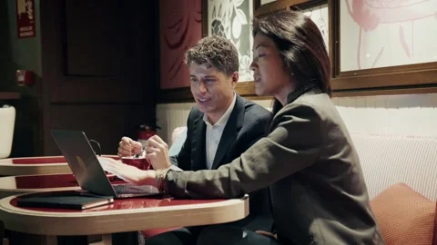 Two professionals seated at a modern cafe working with a laptop Stock-Footage 304289893