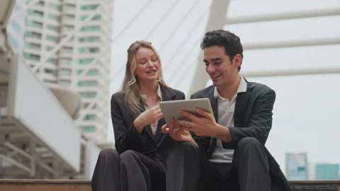 Two professionals share a tablet outdoors, smiling together Vídeo Stock 345198619