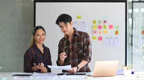 Two professionals web developers standing in bright modern office and smiling to Stock Photos