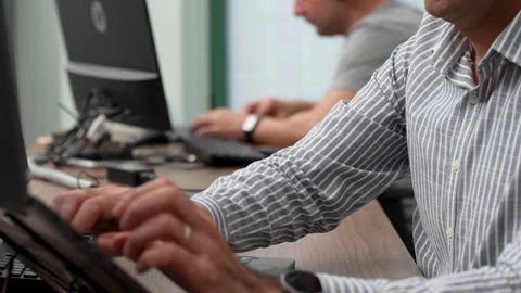 Two professionals working side-by-side on computers in an office Stock Footage 321285062