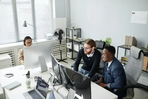 Two program developers in casual clothes sitting in front of computer monitors Stock Photos