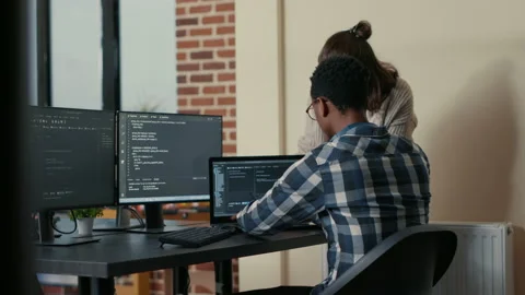 Two programmers doing high five hand gesture at desk with multiple screens Stock Footage 168232459
