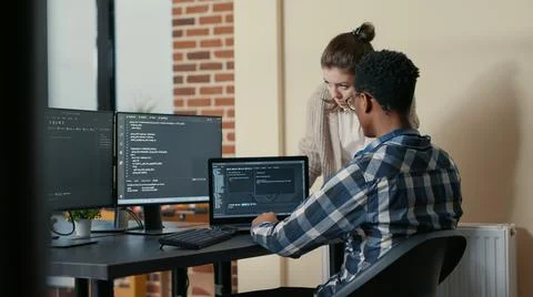 Two programmers doing high five hand gesture at desk with multiple screens Stock-Fotos