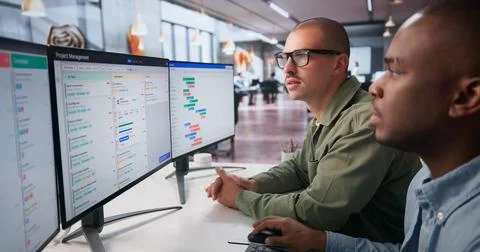 Two Project Managers Discuss Detailed Gantt Chart Schedules On Computer. Stock Photos
