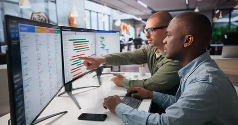 Two Project Managers Work Together On Detailed Gantt Chart Schedules. Stock Photos