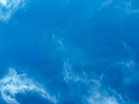 Two propeller-driven aircraft are flying in a blue sky with small white cloud Stock Photos