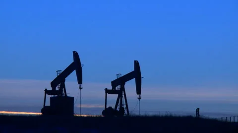 Two pumpjacks pumping crude oil at dusk Video stock 44614723