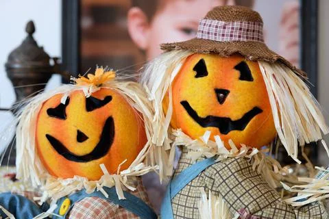 Two pumpkin head scarecrow on display next to a babys portrait Stock Photos