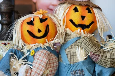 Two pumpkin head scarecrow on display next to a babys portrait Foto stock