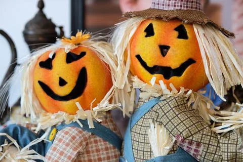 Two pumpkin head scarecrow on display next to a babys portrait Stock Photos