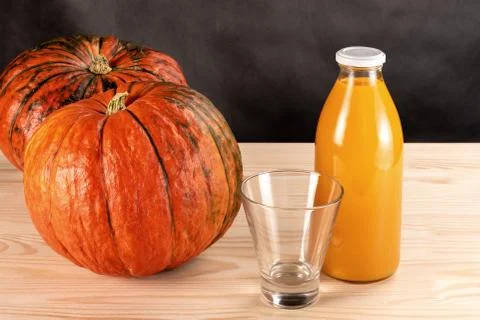 Two pumpkins and a bottle of pumpkin juice on a wooden table. empty juice gla Stock Photos