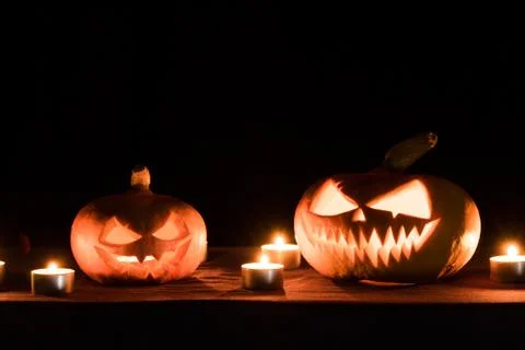 Two pumpkins are on the table, and candles are burning around. Halloween art  Foto stock