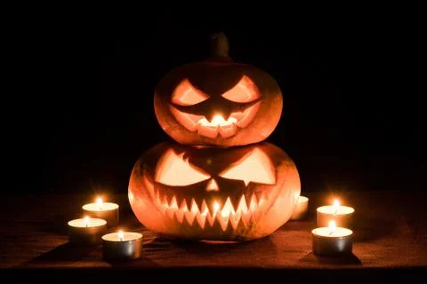 Two pumpkins are on the table, and candles are burning around. Halloween art  Stock Photos