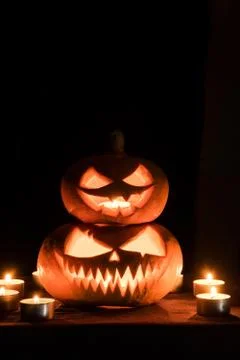 Two pumpkins are on the table, and candles are burning around. Halloween art  Stock Photos