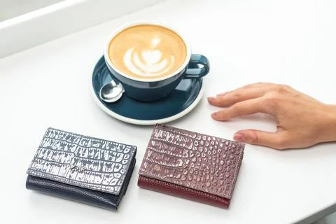 Two purses with a cup of coffee on a white table Stock Photos