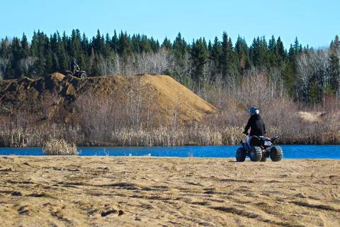 Two quaders take in the view of a pond while riding Stock Photos