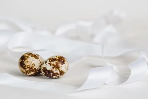 Two quail eggs on a background of white ribbons, selective focus Stock Photos