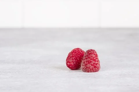 Two raspberries on a gray table. Stock Photos