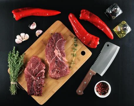 Two raw beef steak with spices, peppers, knife on wooden background Stock Photos