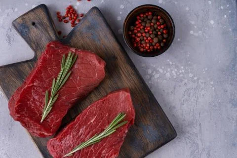 Two raw beef steak with spices and rosemary on table Stock Photos