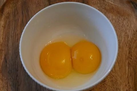 Two raw egg yolks in a white bowl Stockfoto's