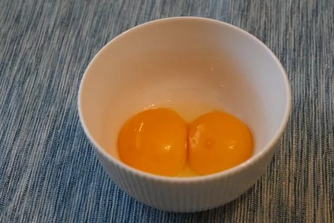 Two raw egg yolks in a white bowl Foto stock