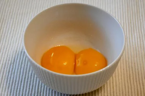 Two raw egg yolks in a white bowl Stockfoto's