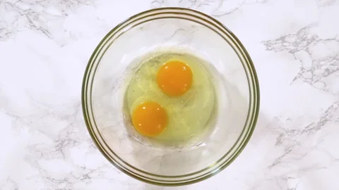Two Raw Eggs in Glass Bowl Stock Footage 319393485