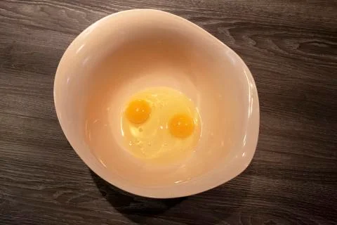 Two raw eggs in large mixing bowl Stock Photos