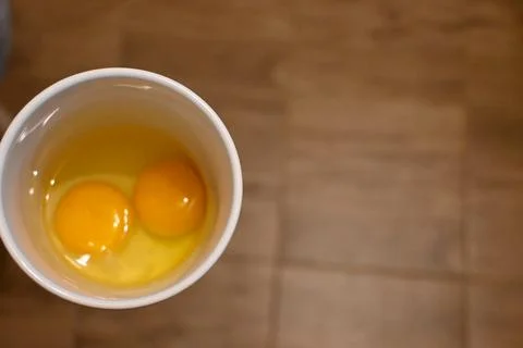 Two raw eggs in a white cup Stock Photos