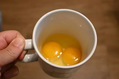 Two raw eggs in a white mug Stock Photos