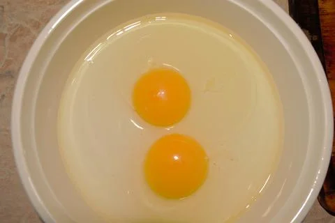 Two raw eggs in a white plate Stock Photos