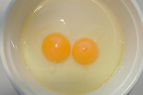 Two raw eggs in a white plate Stock Photos