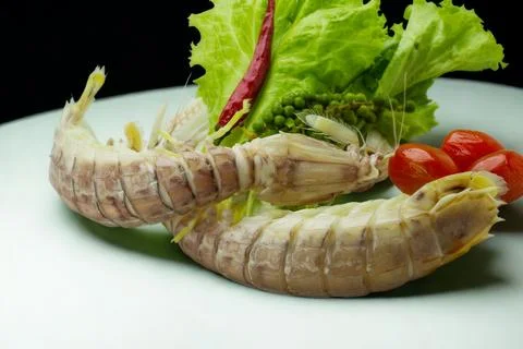 Two raw mantis shrimp served with salad and cherry tomatoes Stock Photos