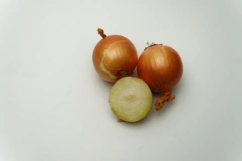 Two raw onions with one sliced on white isolated background Stock Photos