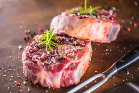 Two raw pieces beef shank on wooden butcher board with fork and knife. Stock Photos