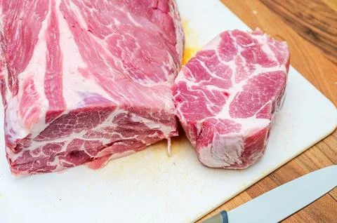 Two raw pork meat cuts on a white cutting board and a knife Fotos de archivo
