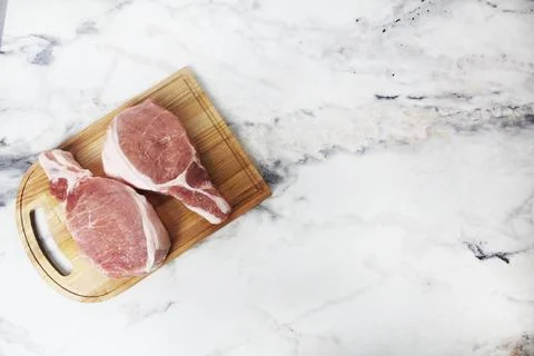 Two raw pork steaks lying on a wooden plank top view copyspace Stock Photos
