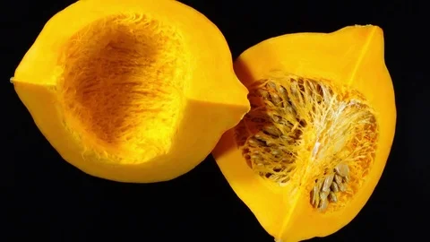 Two raw pumpkin quarters with and without seeds rotates over black background 4K Видео 74060357