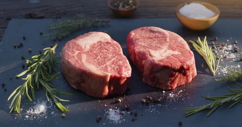 Two raw rib eye steaks with spices and herbs on a stone surface. Stock Footage 137508878