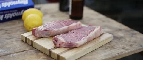 Two raw steak and lemon on wooden board at campsite Stock Footage 69200928