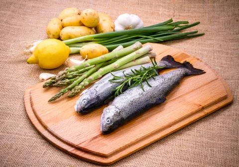 Two raw trout with green asparagus, lemon Stock Photos