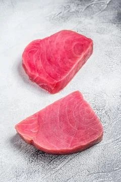Two raw tuna steaks on rustic table. White background. Top view Stock Photos