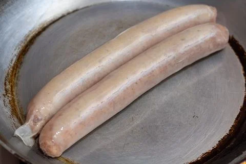 Two raw white sausages lying in a metal frying pan before cooking Stock Photos