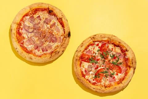 Two ready-made pizzas and a glass of wine on a yellow background Foto stock