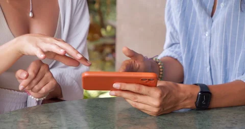 Two recognizable women pointing at the smartphone screen with their hands and Stock Footage 233935876