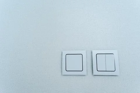 Two rectangular electric blue switches with a brand logo on a white ceiling Stock Photos